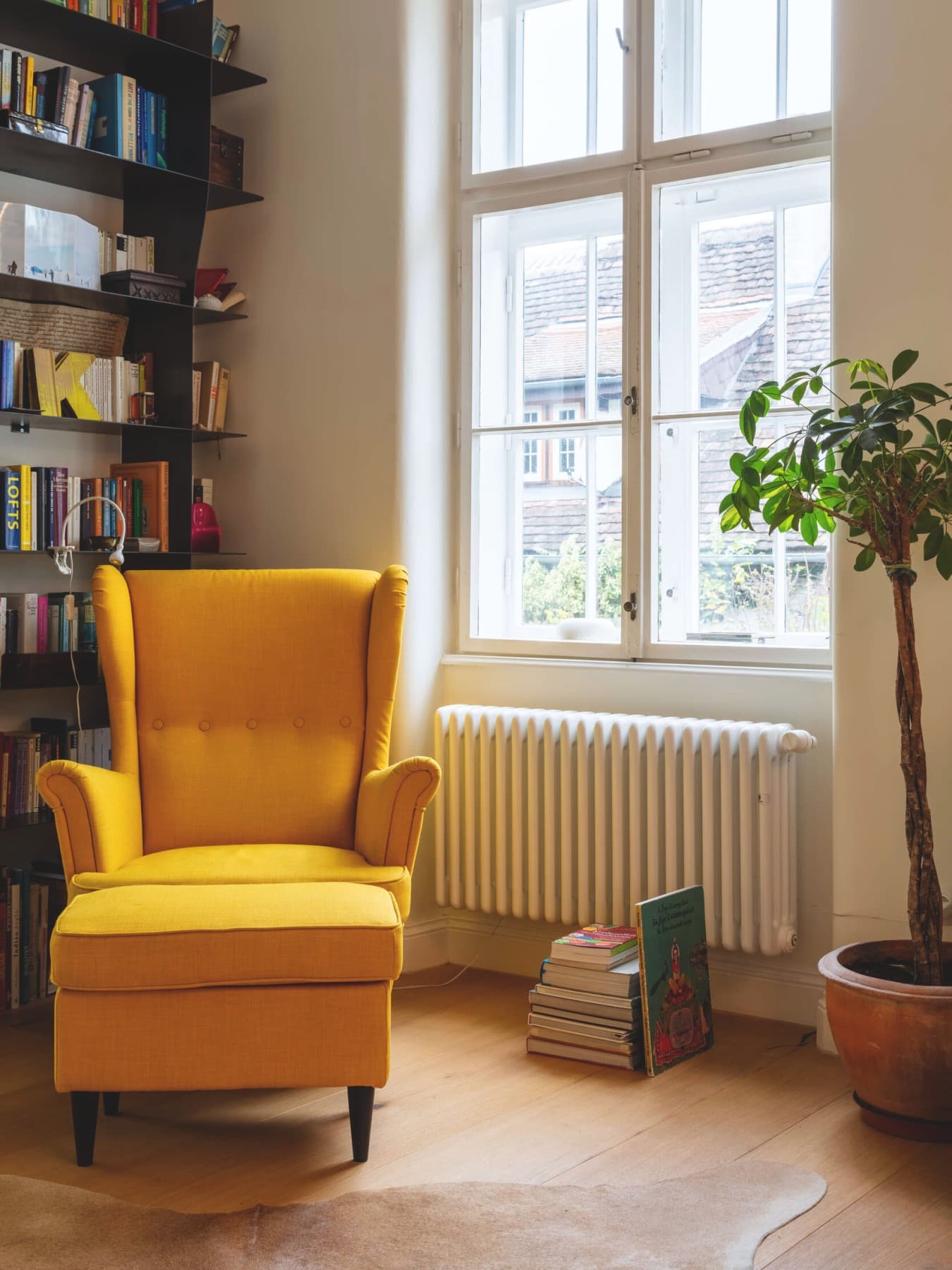Gelber Sessel vor einem Heizkörper der unter einem Fenster montiert ist
