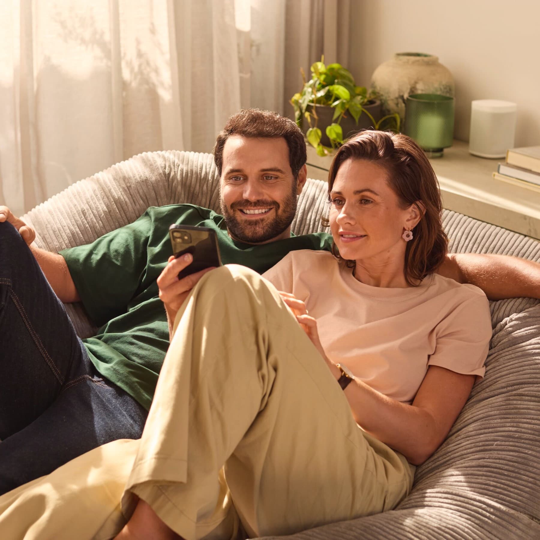 Paar sitzt auf einem Sofa und schaut auf ein Smartphone
