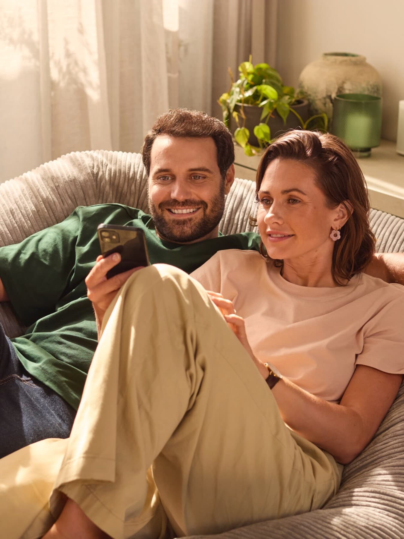 Paar sitzt auf einem Sofa und schaut auf ein Smartphone