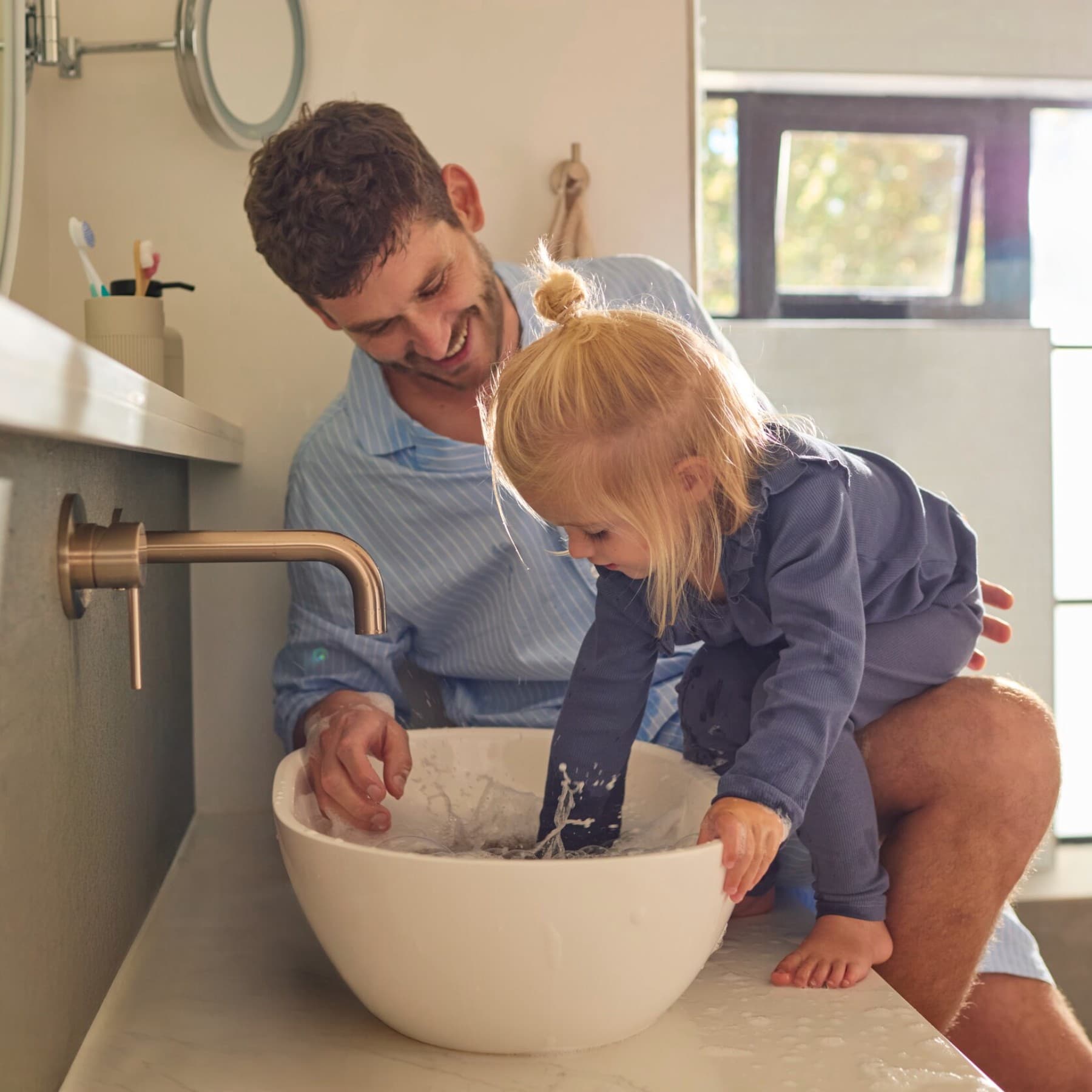 Kind und Vater spielen mit Wasser im Waschbecken