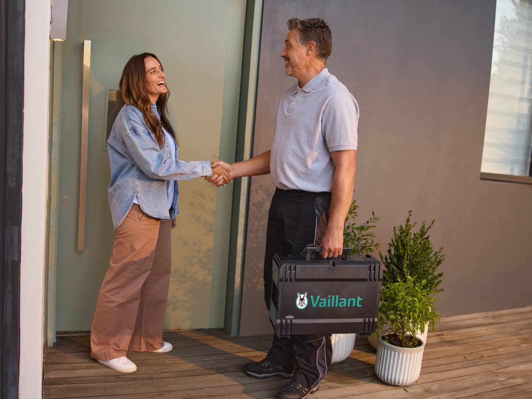 Frau und Vaillant Servicetechniker geben sich vor einer Wärmepumpe die Hand.