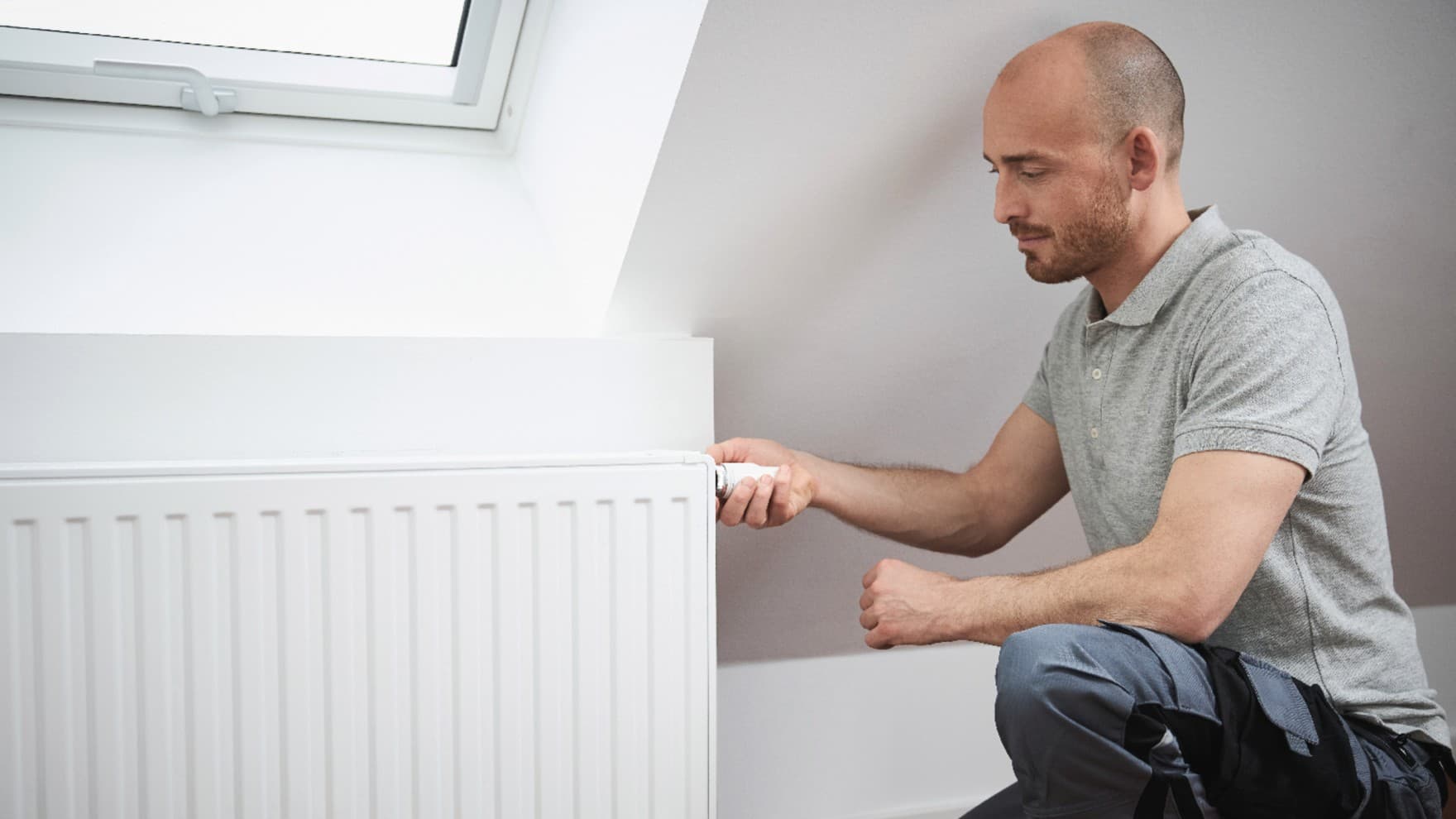 Mann, der den Thermostat an einem Heizkörper einstellt