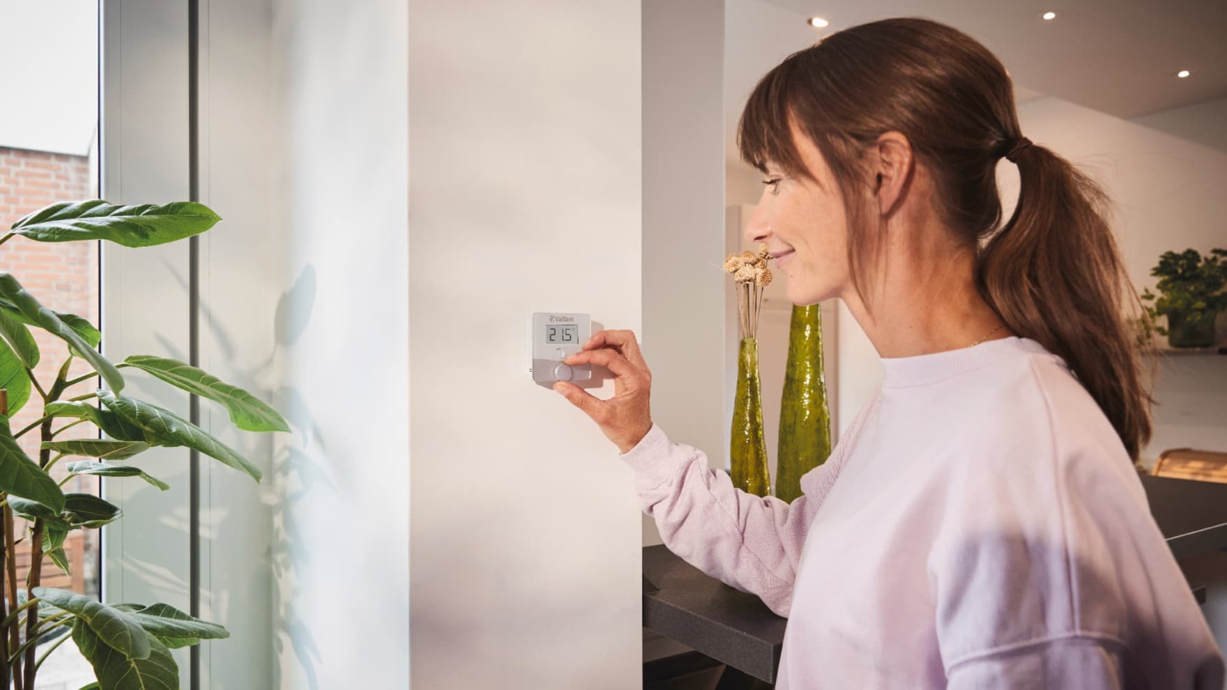 Frau, die den Vaillant-Thermostat sensoROOM verwendet