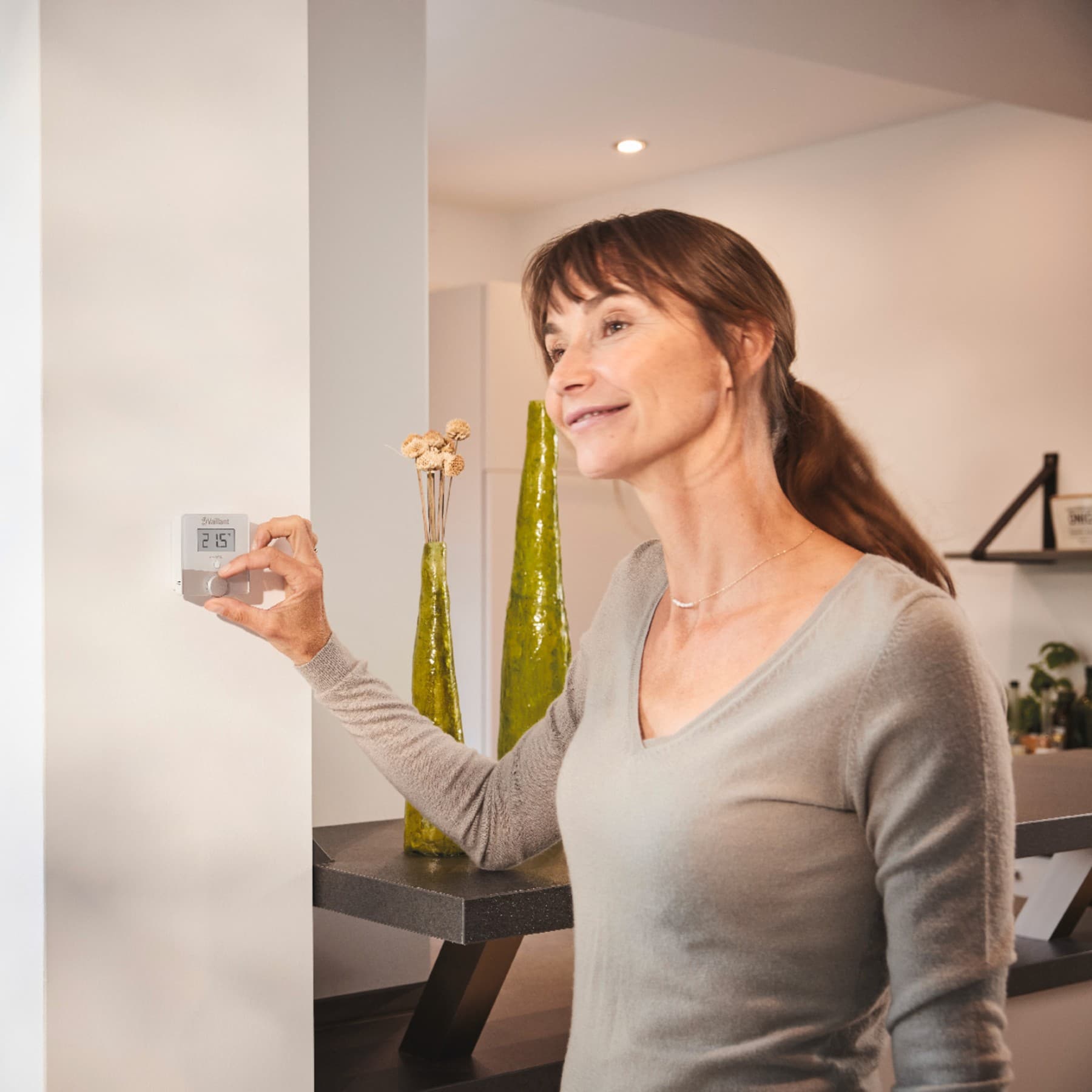 Frau dreht einen Thermostat an der Wand