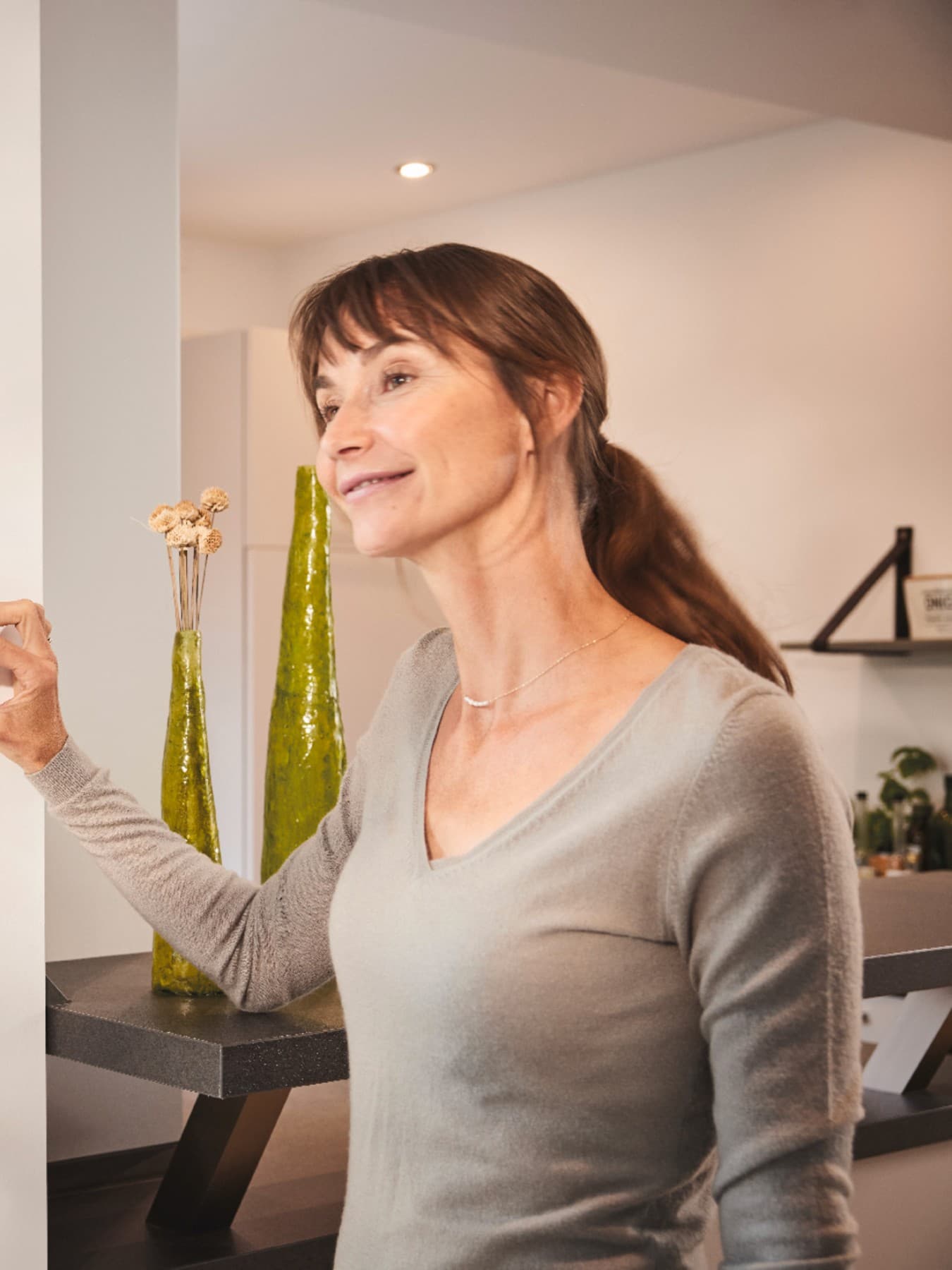 Frau dreht einen Thermostat an der Wand