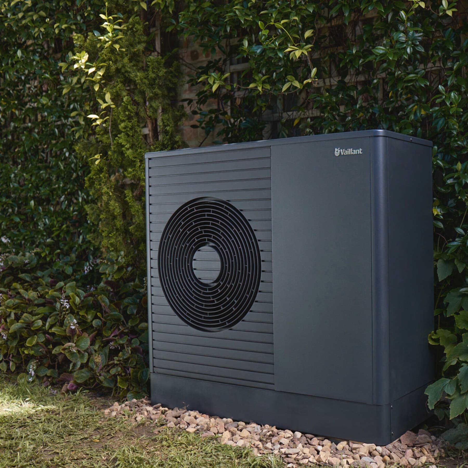 Wärmepumpe aroTHERM vor einem Busch im Garten