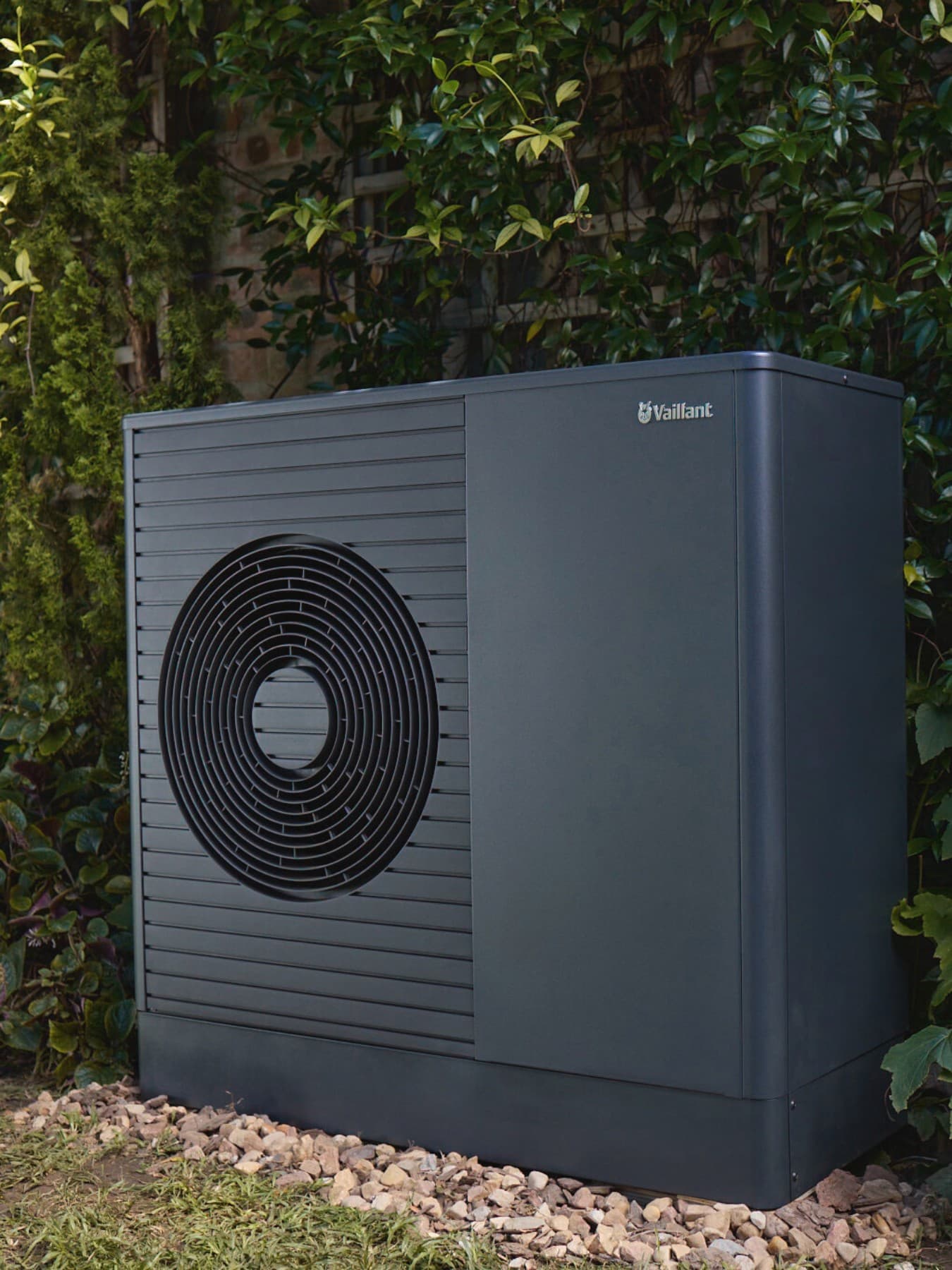 Wärmepumpe aroTHERM vor einem Busch im Garten