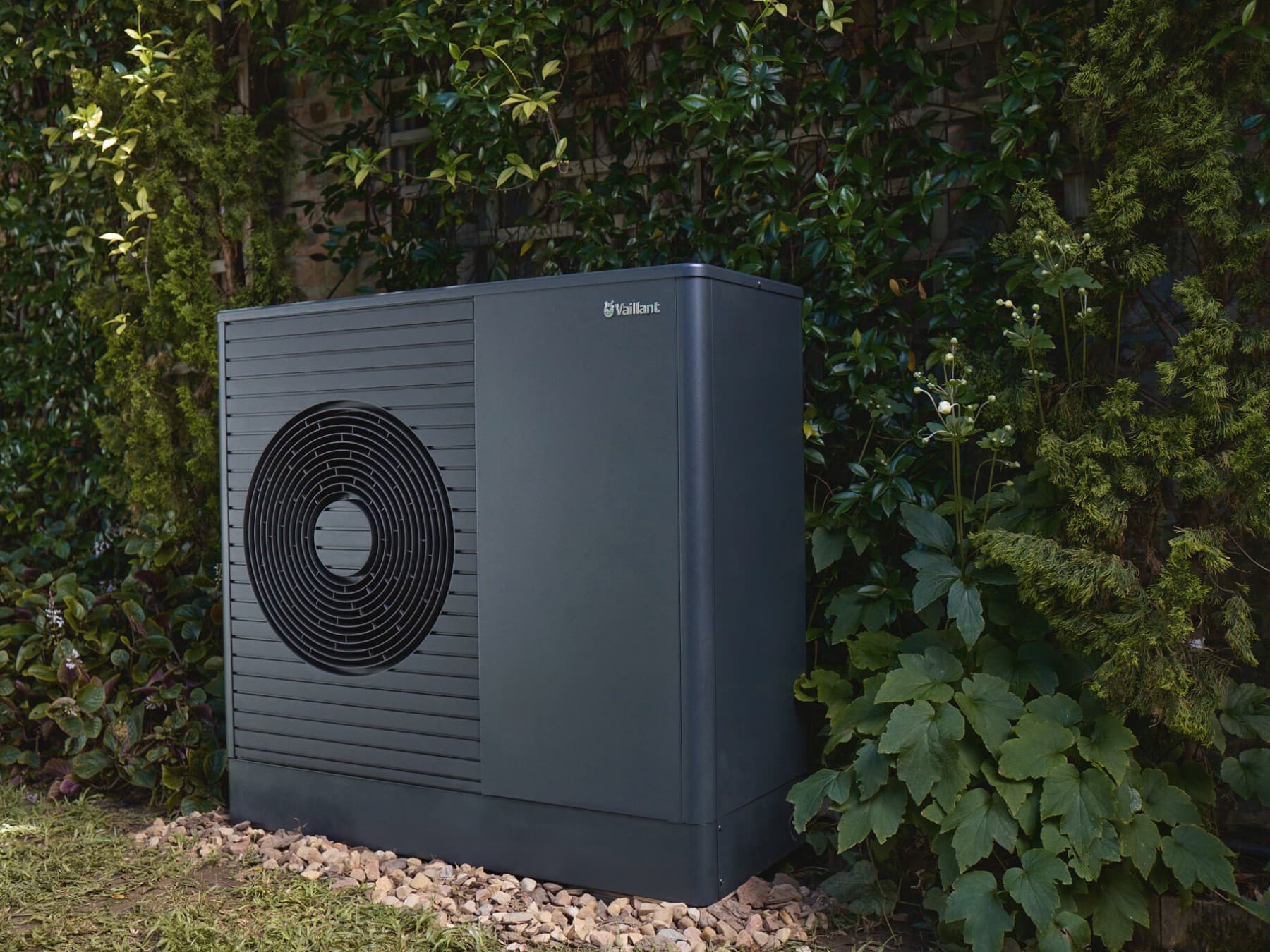 Wärmepumpe aroTHERM vor einem Busch im Garten