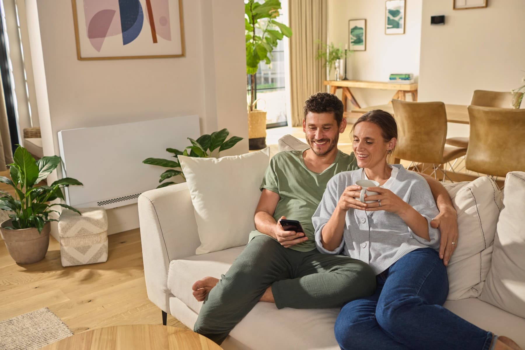 Paar sitzt auf dem Sofa und schaut auf ein Smartphone