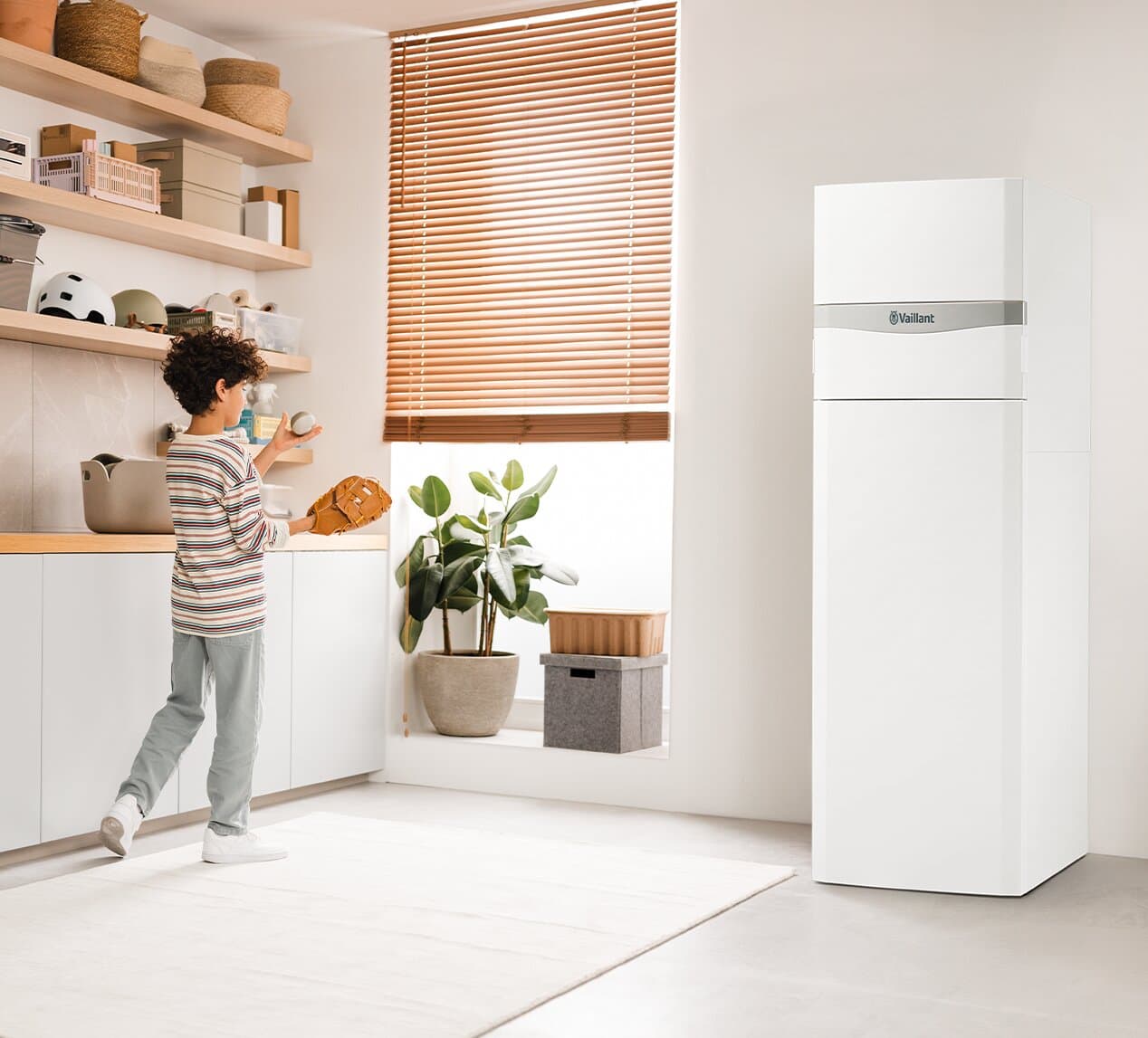 Ein Junge spielt in einem Hauswirtschaftsraum mit dem Vaillant flexoCOMPACT exclusive
