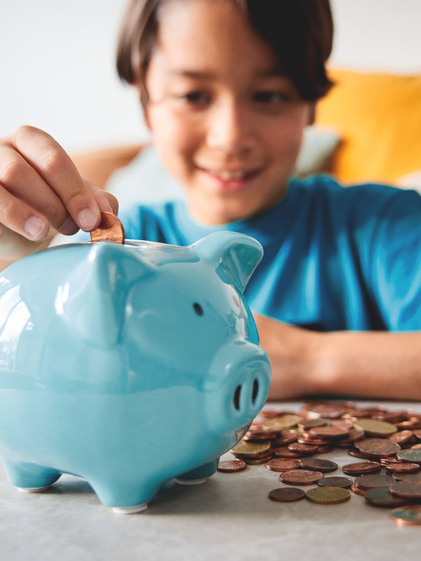 Junge wirft Geld in ein blaues Sparschwein