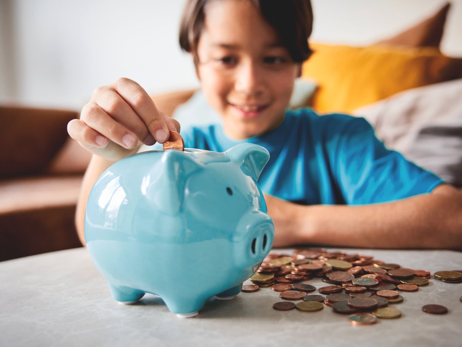Junge wirft Geld in ein blaues Sparschwein