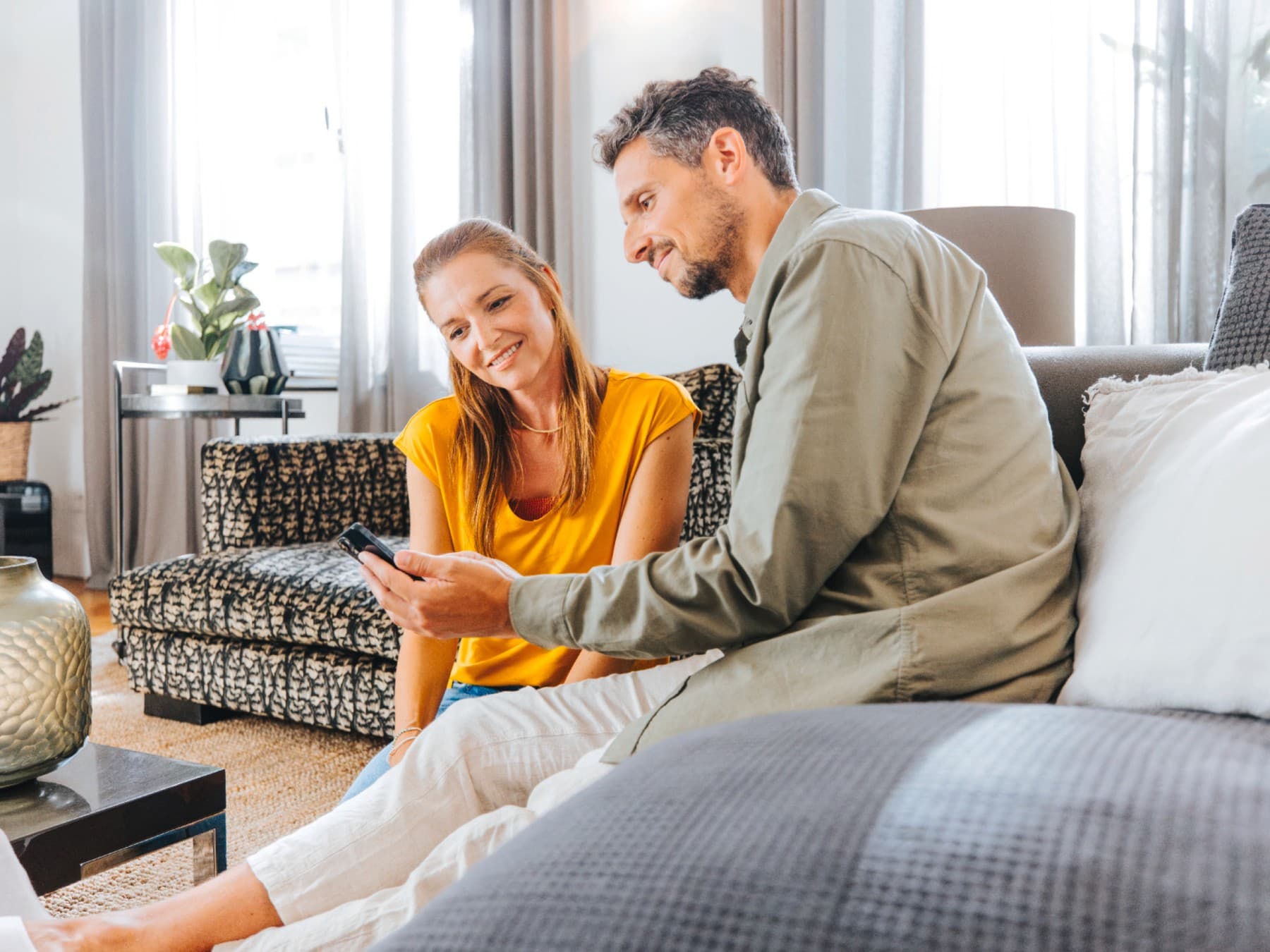 Ein Paar mit einem Smartphone in ihrem Wohnzimmer