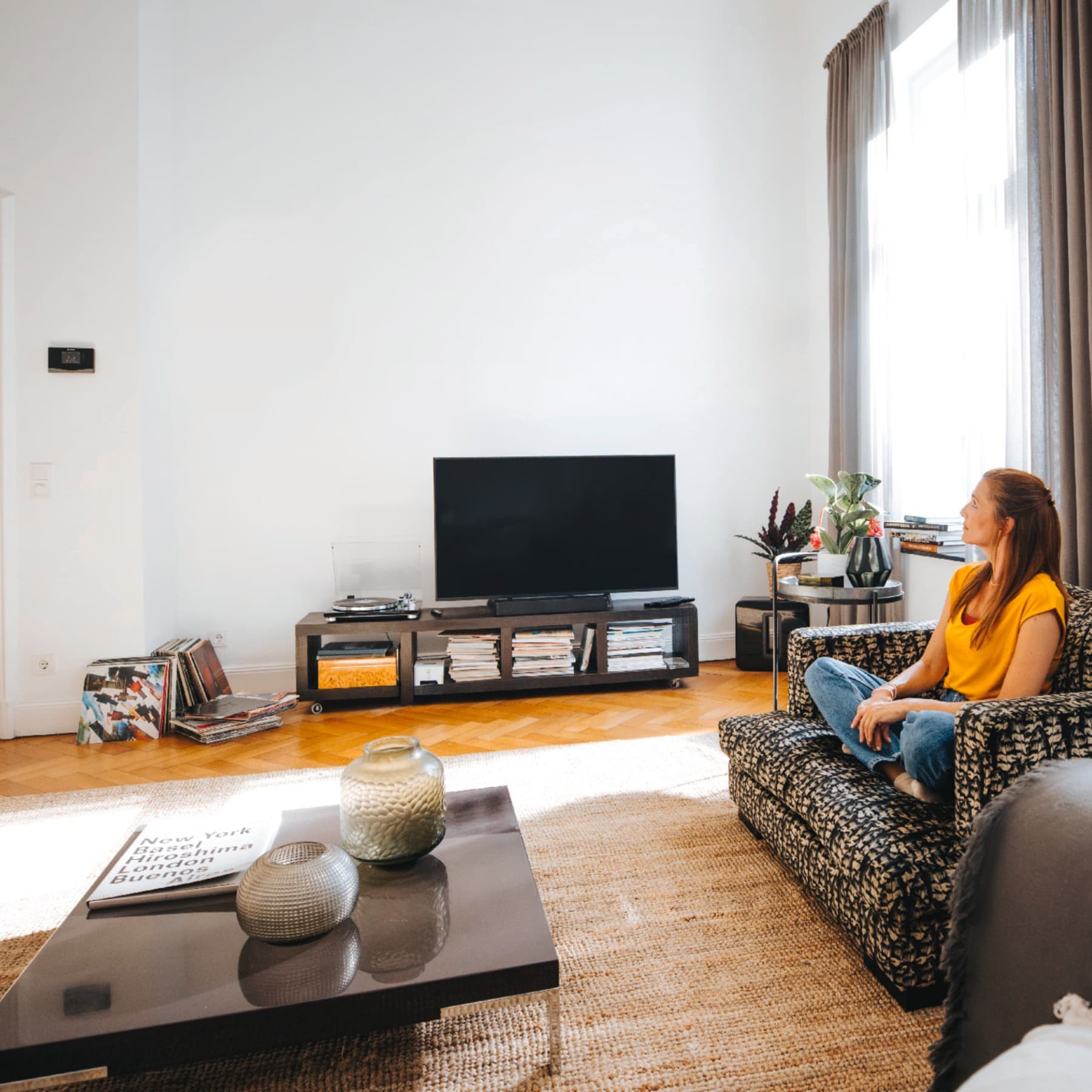 Frau sitzt auf Sofa in einem Wohnraum