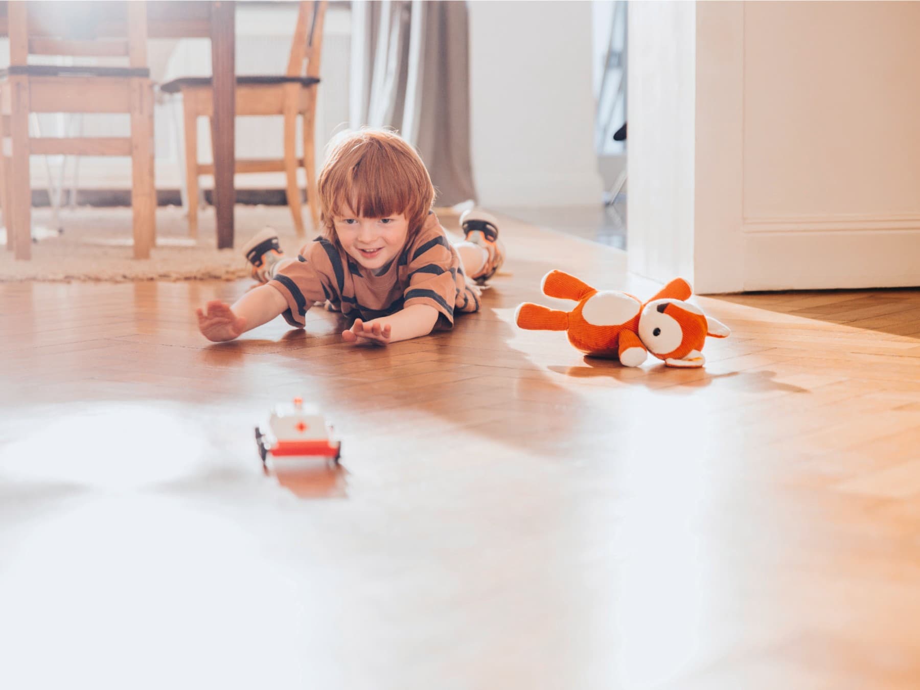 Kind liegt am Boden und spielt mit Spielzeug