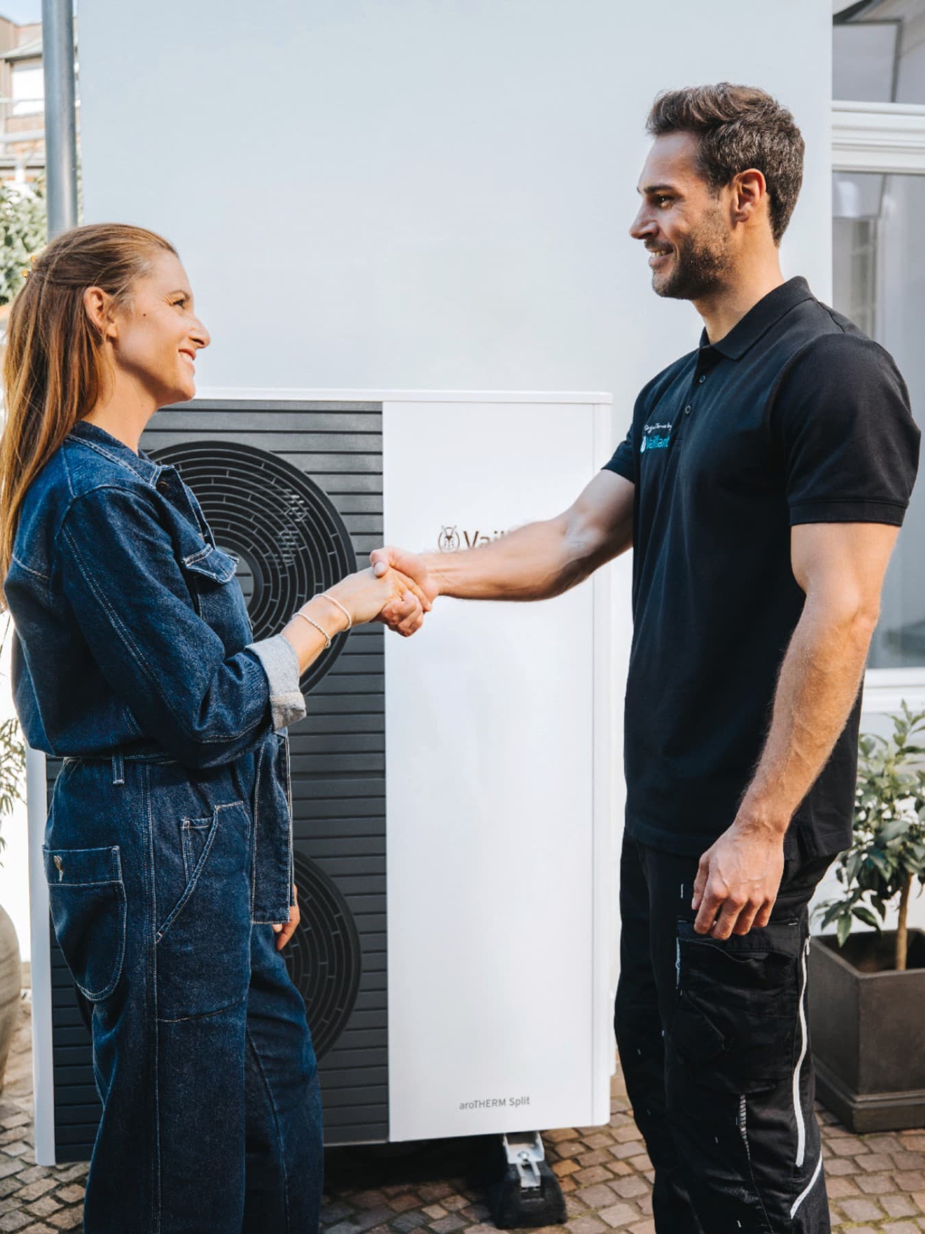 Vaillant Techniker schüttelt Kundin die Hand vor einer Vaillant Wärmepumpe