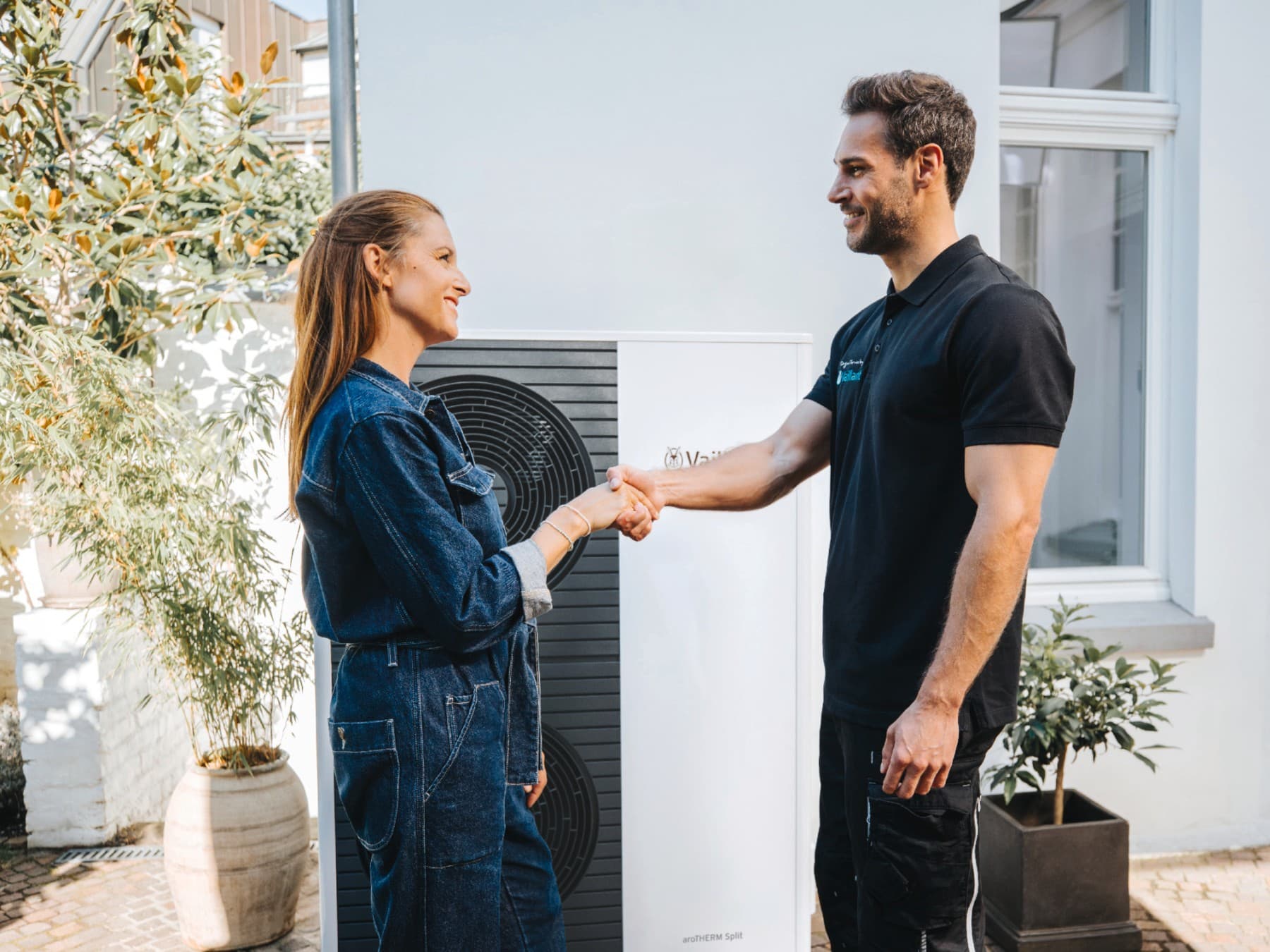 Frau und Installateur geben sich die Hand.