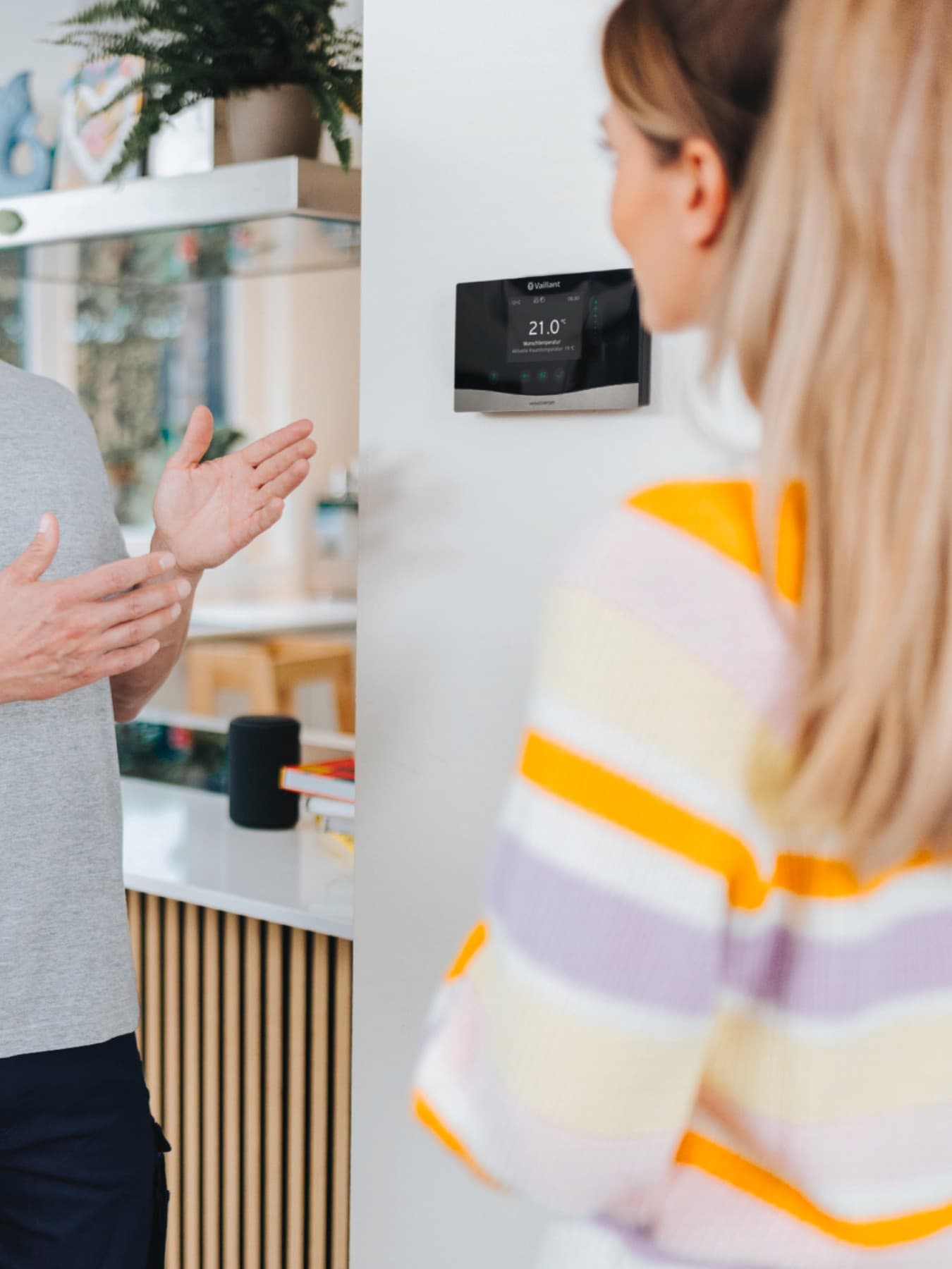 Installateur, der einem Hausbesitzer einen Thermostat an der Wand zeigt