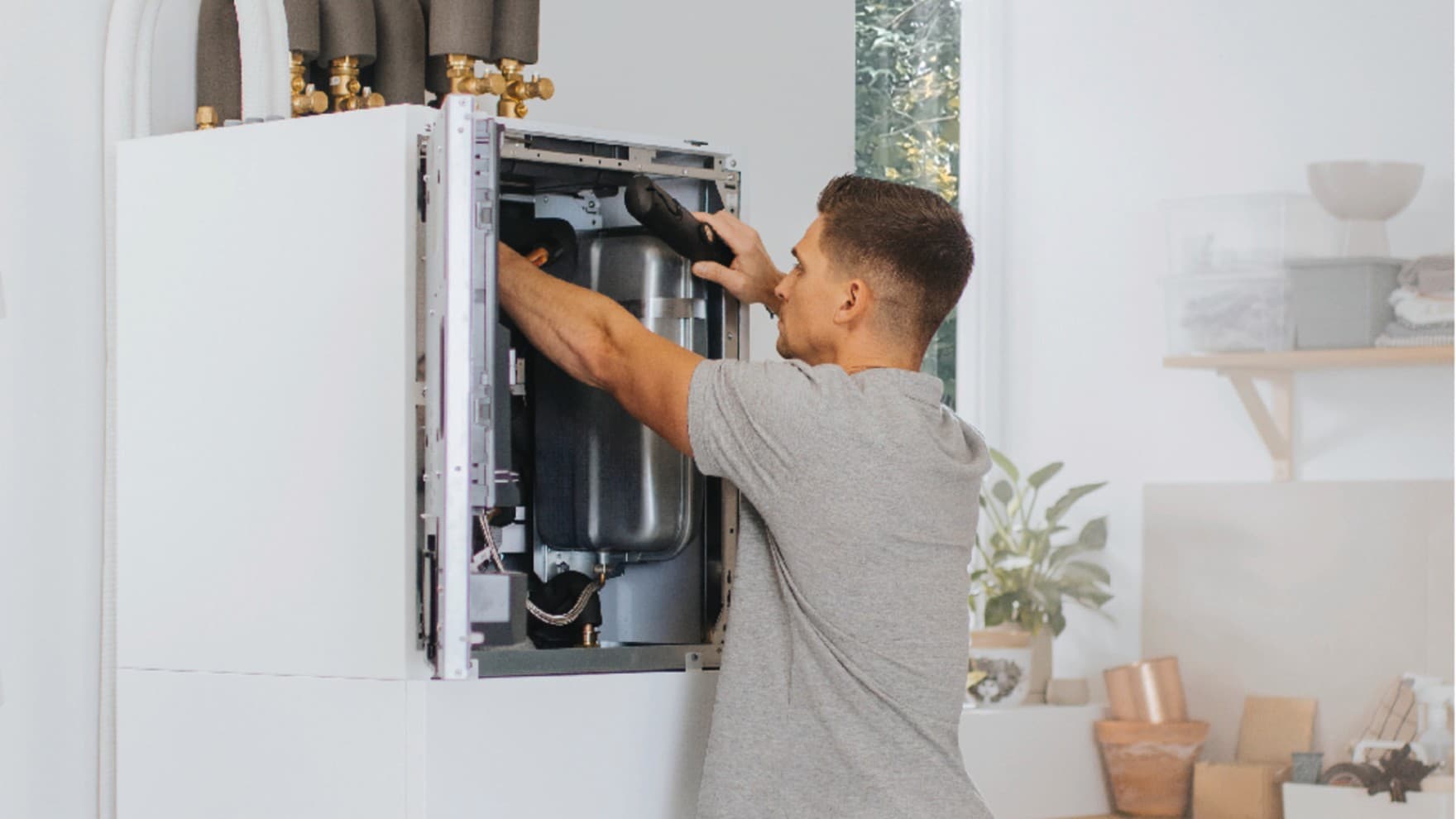 Installateur arbeitet an einer Inneneinheit einer Wärmepumpe