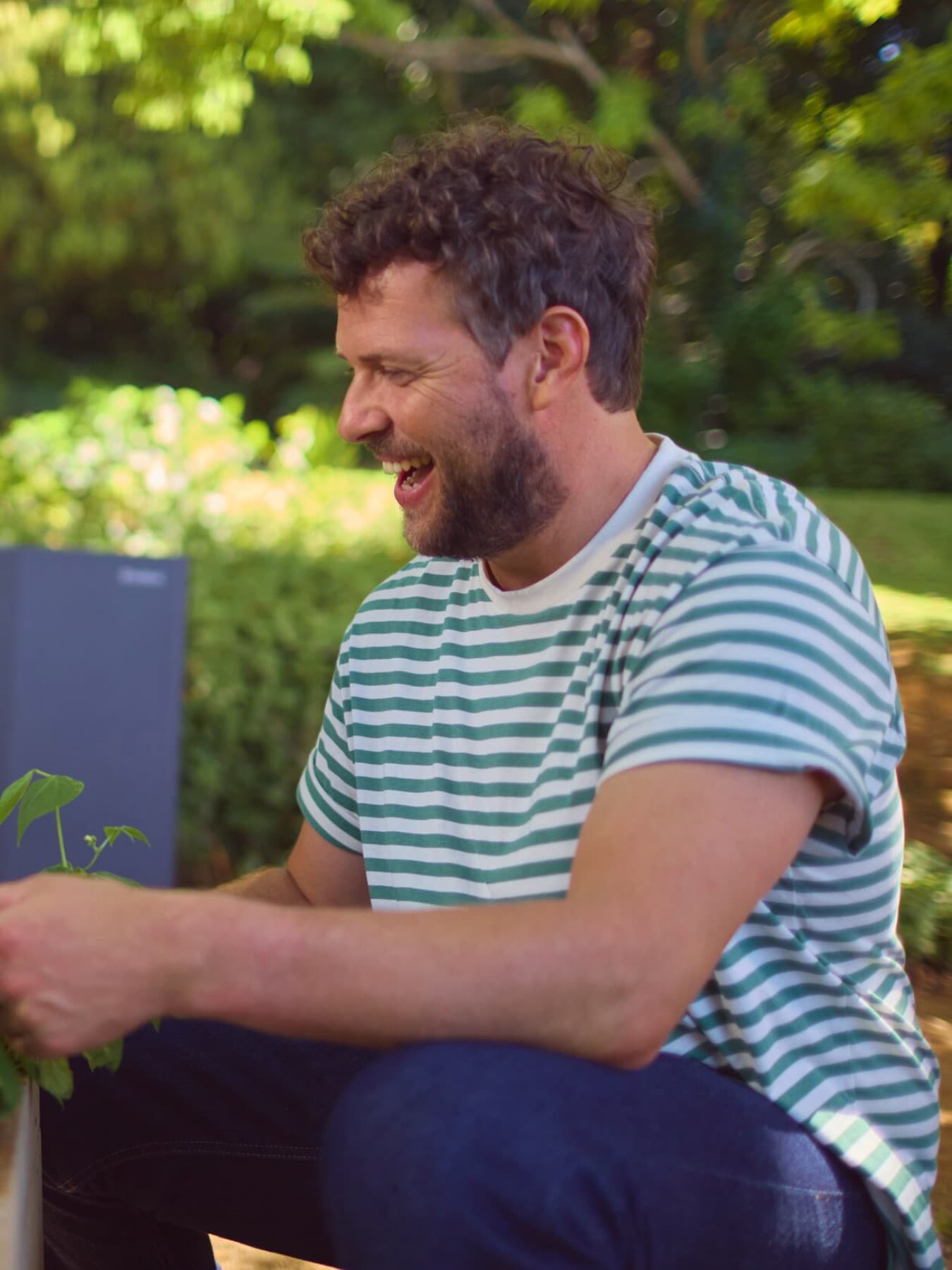 Vater und Sohn gießen die Pflanzen im Garten vor einer Wärmepumpe