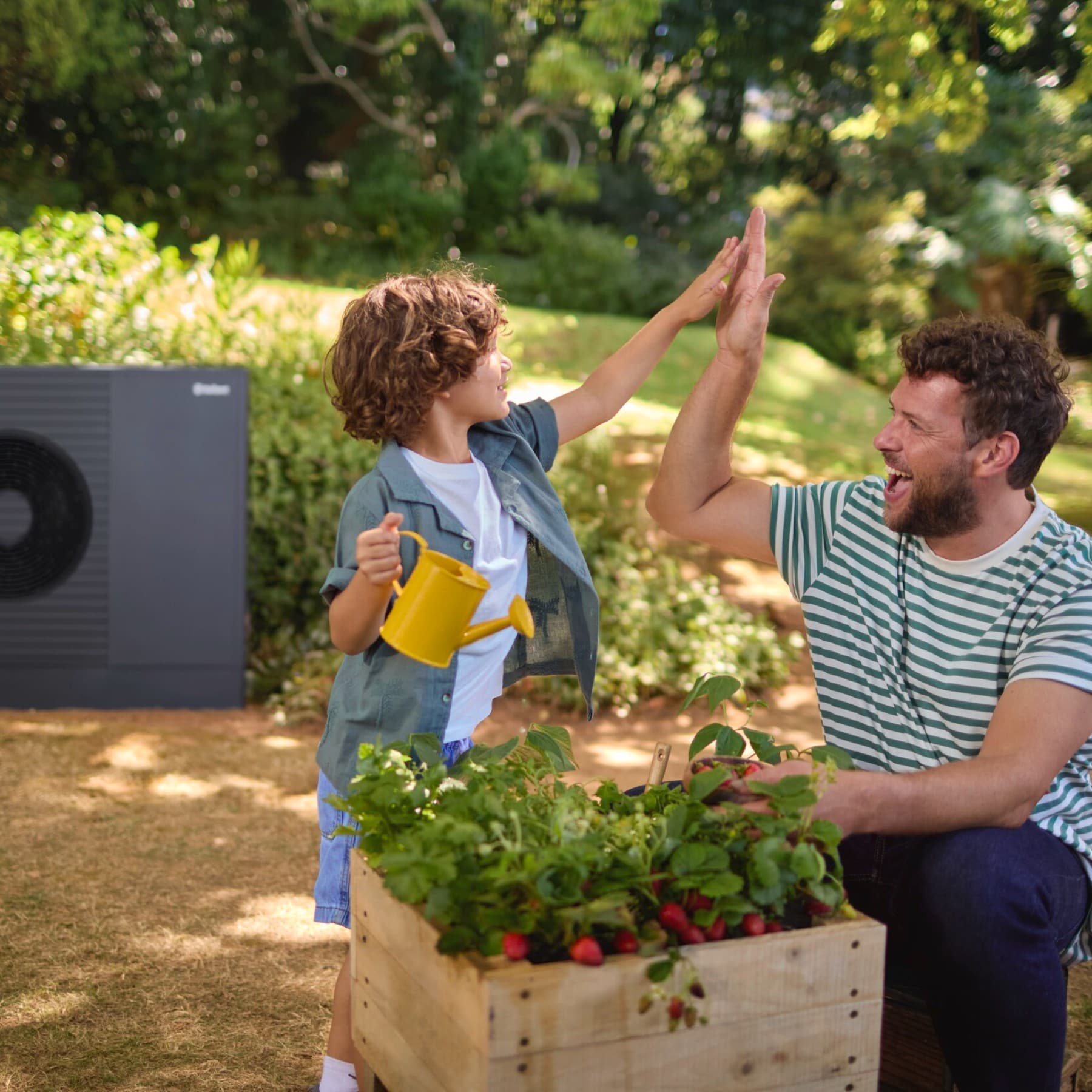 Mann und Kind spielen im Garten vor einer Wärmepumpe