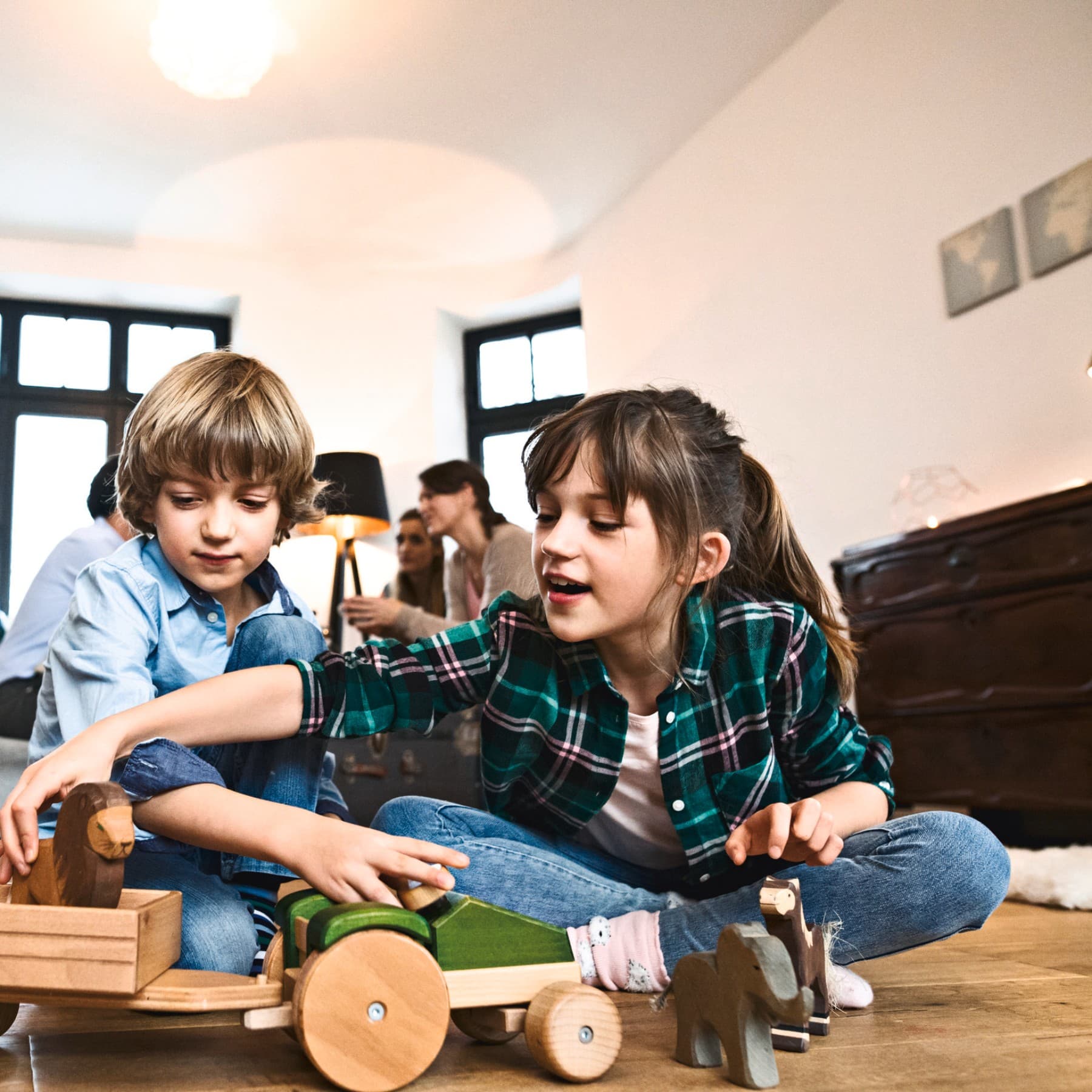 Kinder spielen am Fußboden mit einem Holzspielzeug