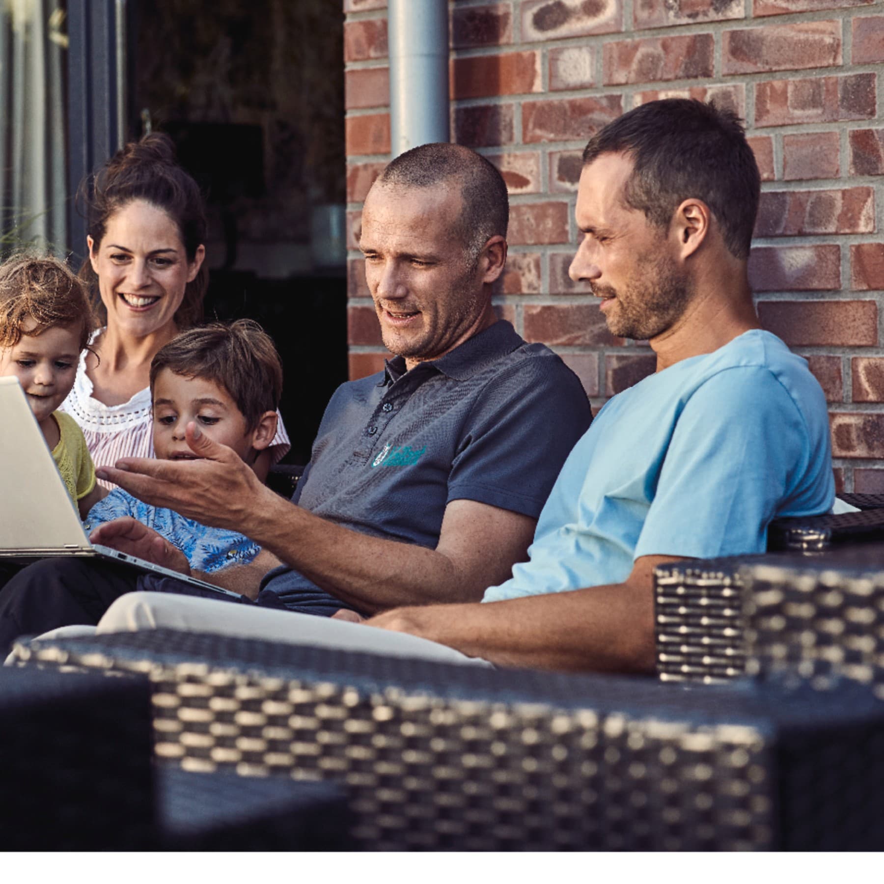 Techniker erklärt einer Familie die Heizung auf einer Gartenbank