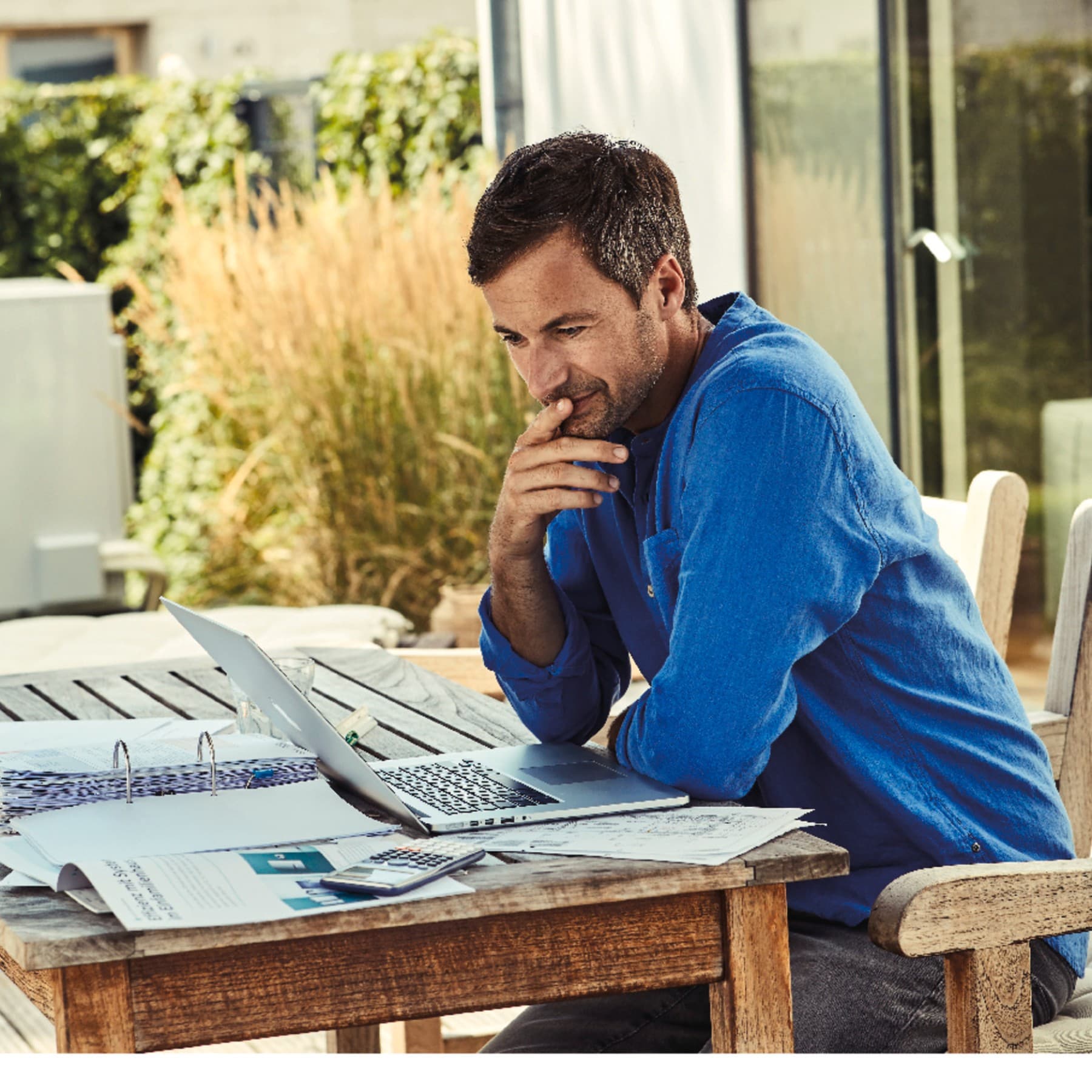 Mann sitzt am Laptop im Garten und recherchiert Wärmepumpen relevante Themen