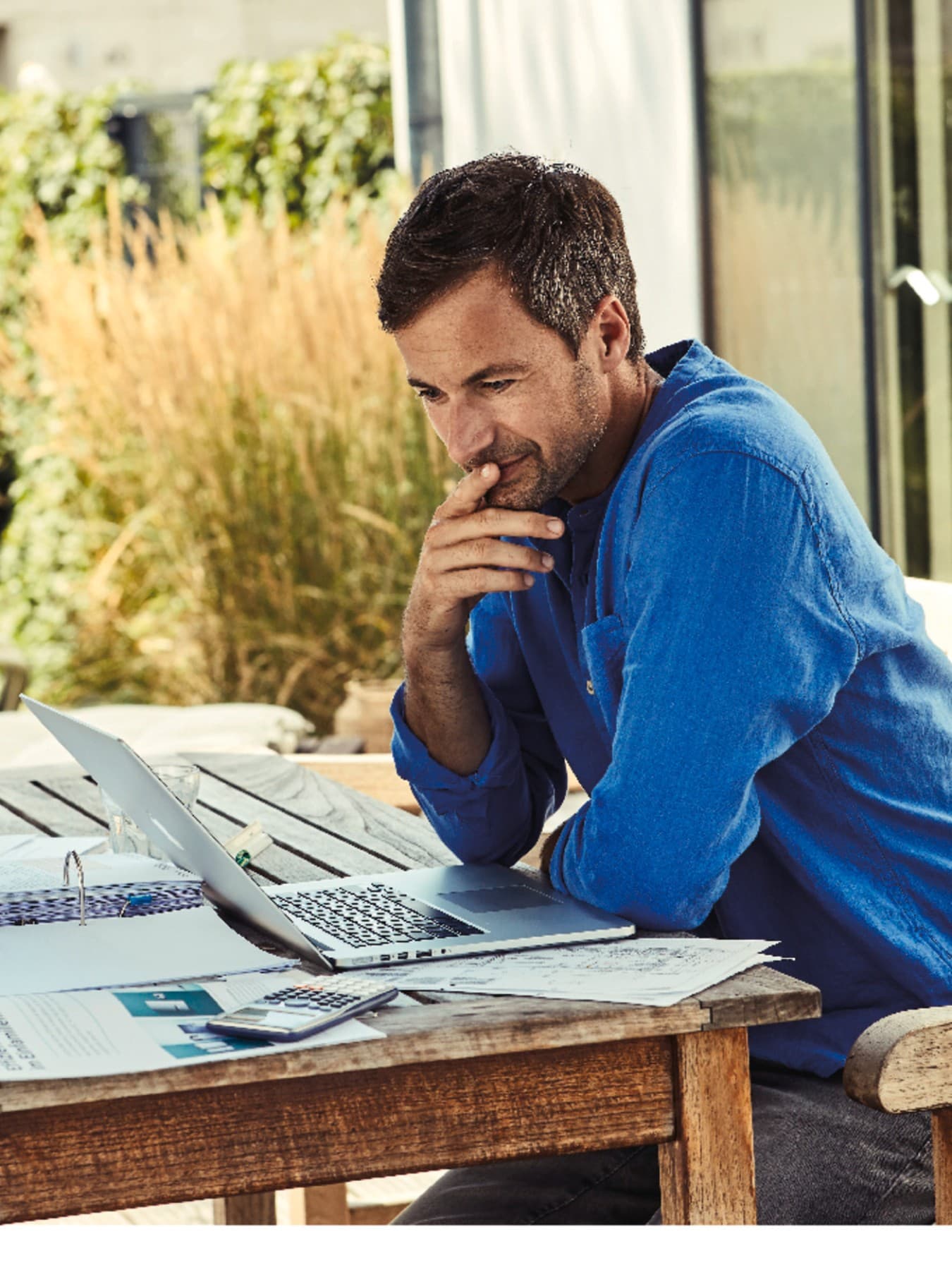 Mann sitzt am Laptop im Garten und recherchiert Wärmepumpen relevante Themen