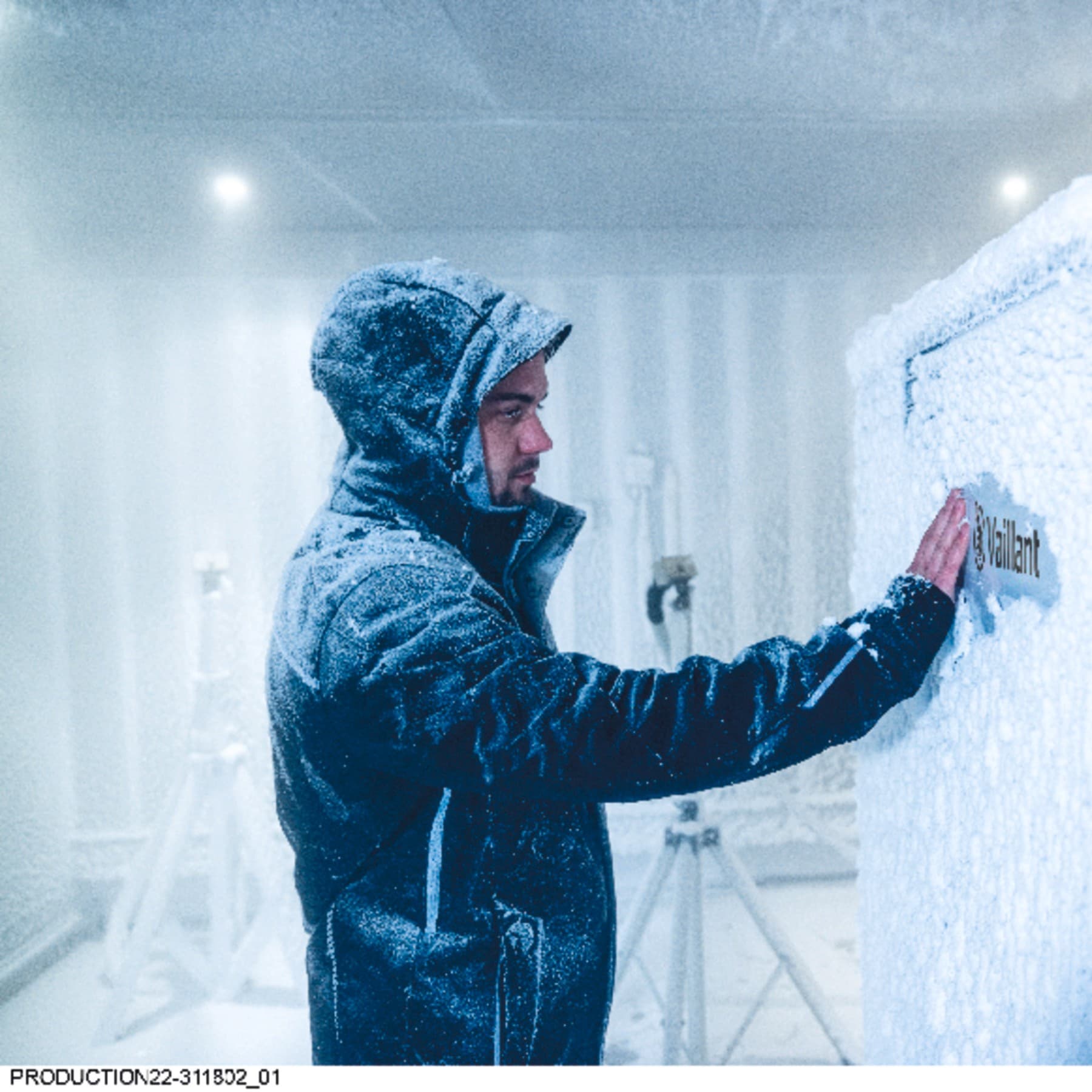 Ein Mann mit Winterjacke im Testzentrum von Vaillant neben einer verschneiten Wärmepumpe