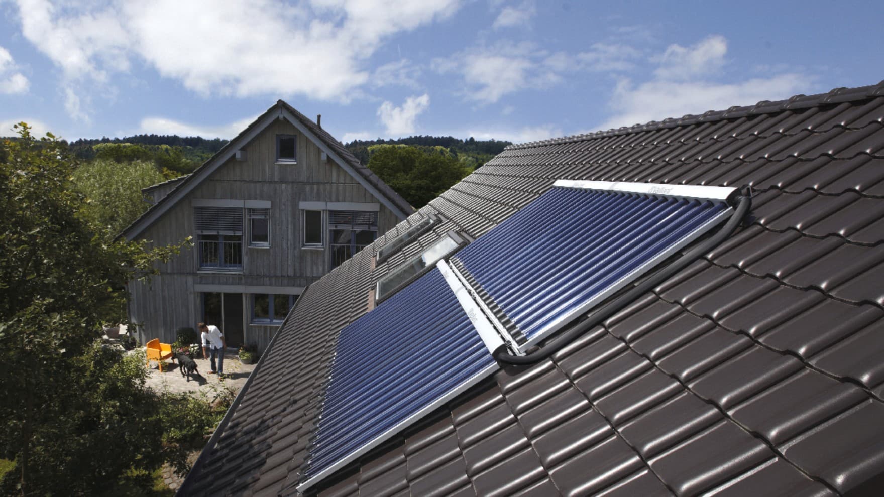 Ein Dach mit Solarmodulen und im Hintergrund ein Haus