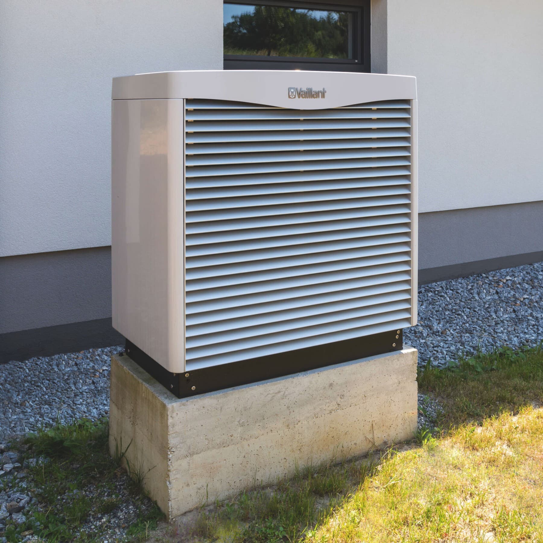 Wärmepumpe auf einem Sockel vorm Haus