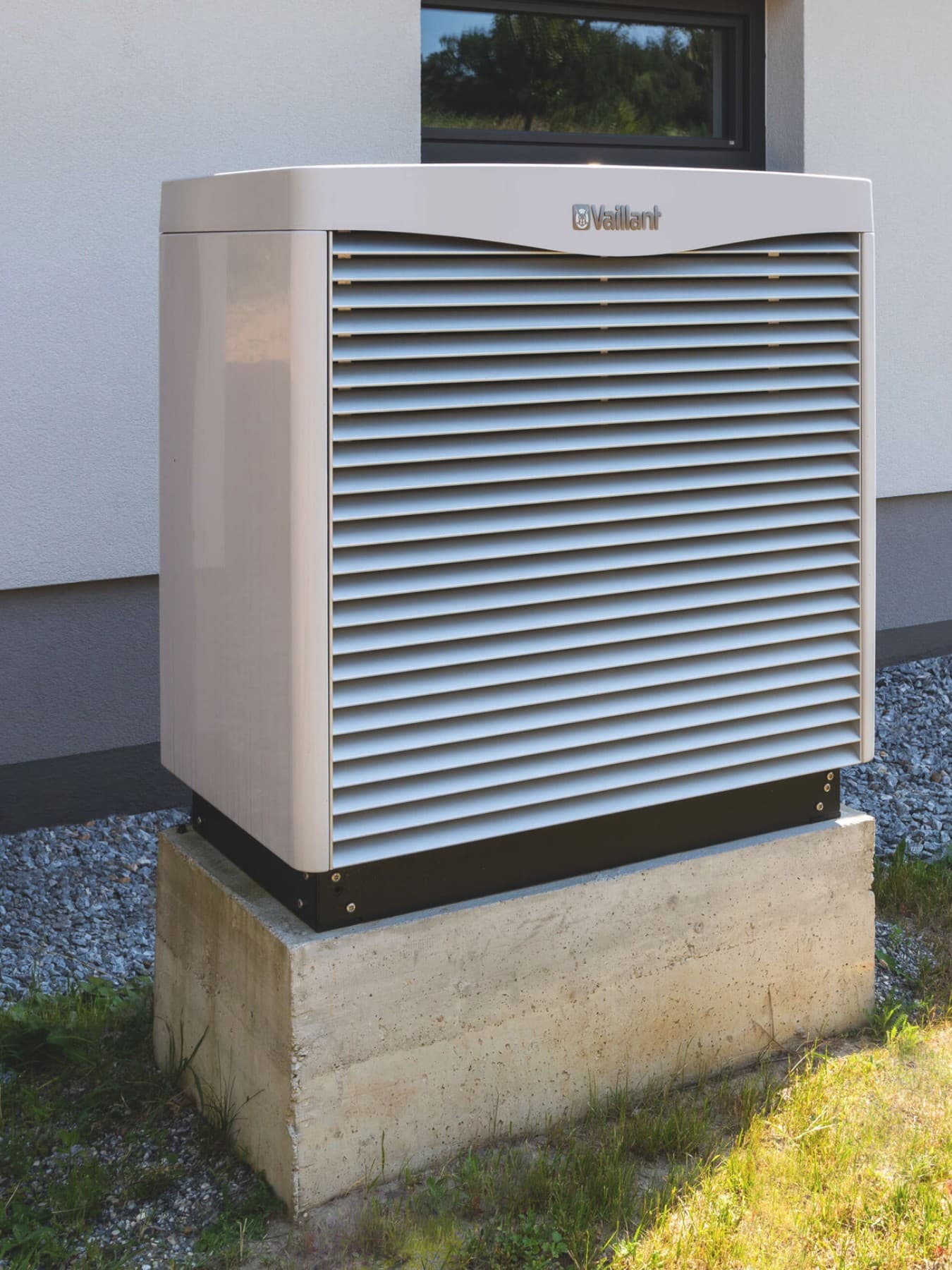 Wärmepumpe auf einem Sockel vorm Haus