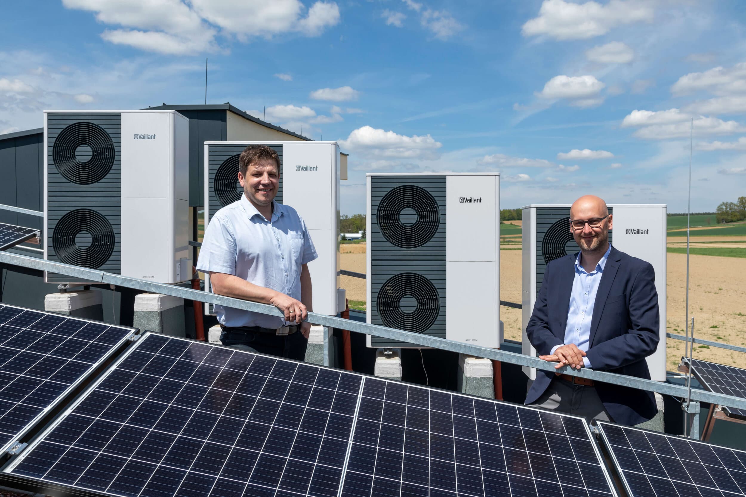 Zwei Männer hinter einer PV Analge und vor Vaillant Wärmepumpen
