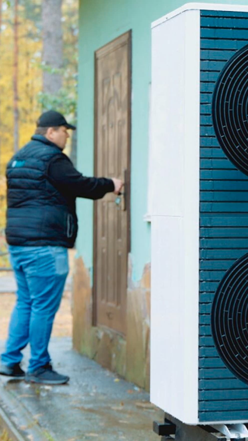 Ein Mann öffnet eine Holztür, im Vordergrund steht eine Vaillant Wärmpeumpe