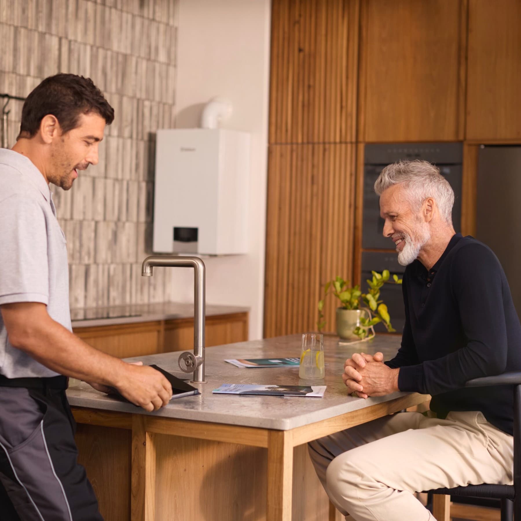 Techniker redet mit Mann in Küche und Vaillant Gerät im Hintergrund